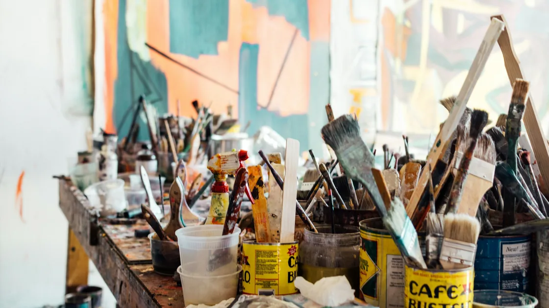 Pinceles de pelo y cerda de distintos tamaños dispuestos sobre una mesa de madera de taller